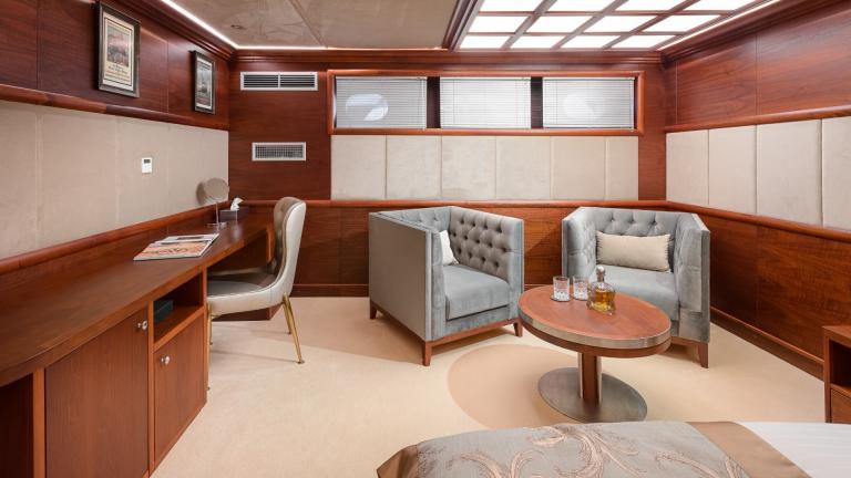 The seating area in the master cabin consists of two cosy grey designer armchairs and a fine table.